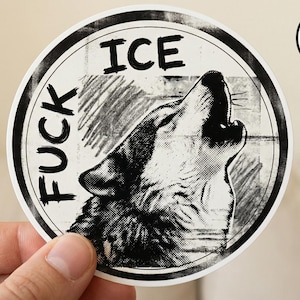 May include: A round, black and white sticker featuring a howling wolf illustration. The sticker has the words "FUCK ICE" in a circular design around the wolf. A smaller circle with "BUY 5 GET 1 FREE" is in the upper right corner.