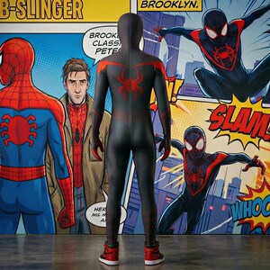 May include: A person in a black and red Spider-Man costume stands in front of a comic book-style mural. The mural features Spider-Man and the text "WEB-SLINGER", "BROOKLYN", "SLAM", and "WHOOSH!"