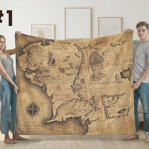 Può includere: Una grande coperta rettangolare con una mappa dettagliata della Terra di Mezzo, con regioni come Gondor e Mordor etichettate in testo nero. La coperta ha un aspetto vintage, simile alla pergamena, con un disegno a rosa dei venti.