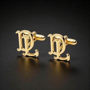 May include: A pair of gold cufflinks, each featuring the intertwined letters "DL" in an ornate font. The cufflinks are presented against a dark backdrop, highlighting their shiny surface and detailed craftsmanship. These are suitable for formal occasions.