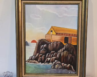 May include: Vintage framed painting depicting Noah's Ark on a rocky cliffside at sunset. The ark is a golden yellow, set against a sky of pale blue and orange. The painting is signed and framed in a gold-toned frame.