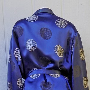 May include: A blue satin robe with a gold pattern of Chinese symbols. The robe has a sash and long sleeves.