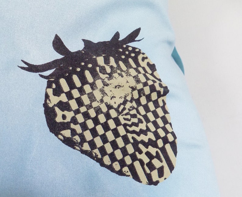 Puede incluir: Una camiseta azul claro con un dise&ntilde;o a cuadros en blanco y negro de un coraz&oacute;n con cuernos.