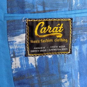 May include: A blue blazer with a black label that reads "Carat men's fashion clothing" with the locations "Anaheim, Costa Mesa, Garden Grove, Huntington Beach" printed below.