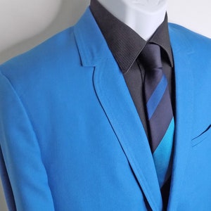 May include: A bright blue blazer with a black button-down shirt and a striped tie. The tie has blue, black, and turquoise stripes.