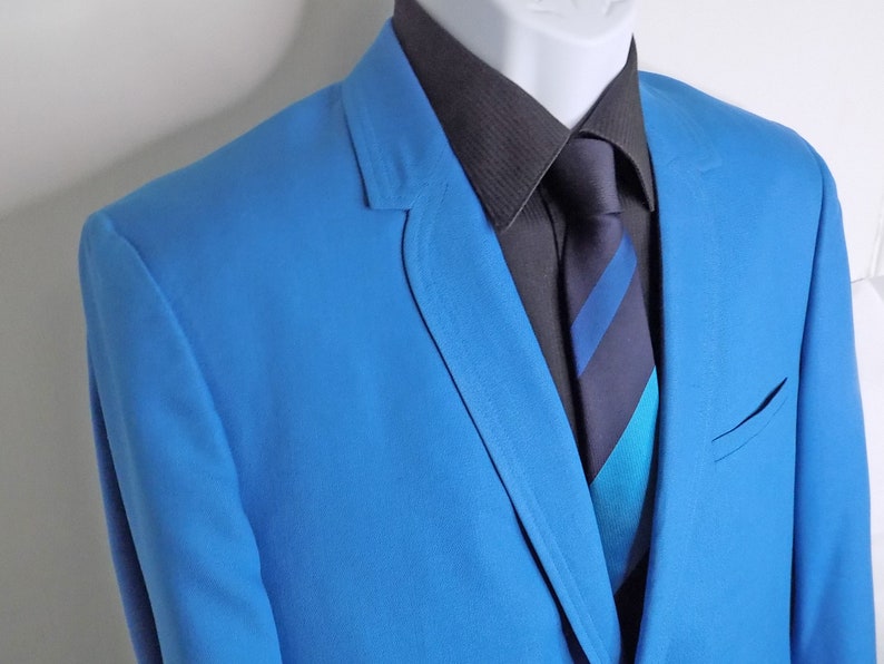 May include: A bright blue blazer with a black button-down shirt and a striped tie. The tie has blue, black, and turquoise stripes.