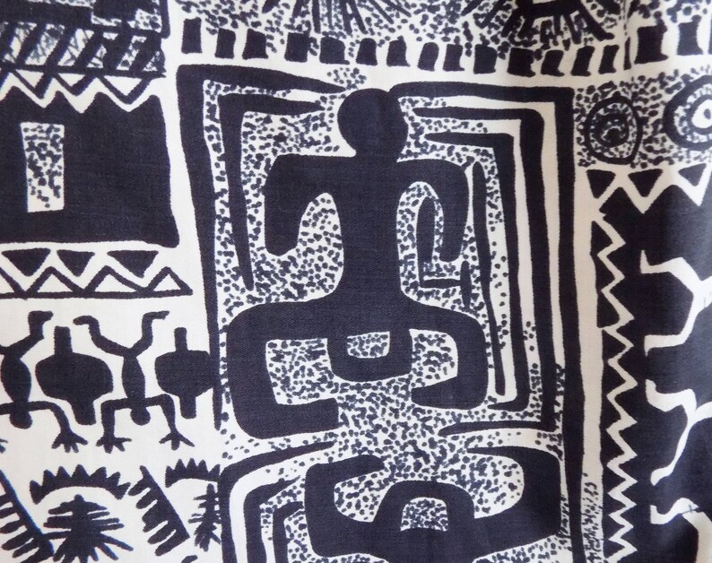 Pu&ograve; includere: Tessuto bianco e nero con un motivo ripetitivo di forme geometriche e figure stilizzate. Il tessuto presenta un disegno di una persona con braccia e gambe distese, circondata da forme astratte.