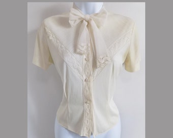 1940s-50s Demure cream nylon lacey blouse with tie that is perfect for a bow, pearl-like fancy buttons, unreadable tag, pintuck pleats