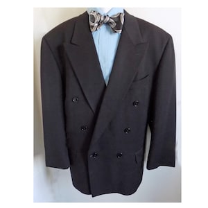 May include: A black double-breasted blazer with six buttons, a light blue dress shirt, and a patterned bow tie. The blazer has a classic design with notched lapels and a tailored fit. The bow tie features a black and silver design.