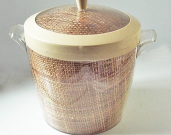 May include: A beige plastic ice bucket with a woven brown lid and a clear plastic lid. The bucket has two handles.