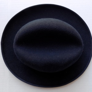 May include: A dark navy blue hat with a rounded crown and a wide brim. The hat is made of a soft, felt-like material. The hat is a classic style, suitable for various occasions.