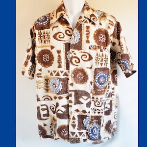 Puede incluir: Una camisa blanca de manga corta con un patrón geométrico marrón y azul. La camisa tiene un frente abotonado y un cuello.