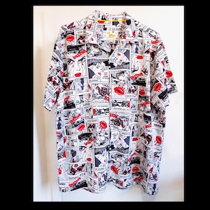 May include: A white button-up shirt with a comic book print featuring black and red illustrations of women's faces and lips. The shirt has a collar and short sleeves.