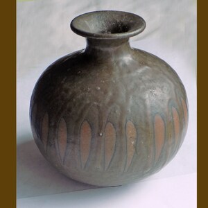 Könnte beinhalten: Eine kleine, runde, dunkelgraue Keramikvase mit brauner Glasur und einer schmalen Öffnung. Die Vase hat ein Muster aus vertikalen braunen Linien.