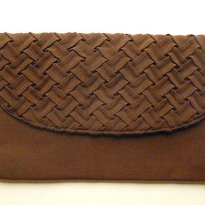 May include: A brown clutch purse with a woven pattern on the flap. The purse has a rectangular shape with a curved flap and a textured, solid-colored body. A small, amber-colored clasp is visible on the side.