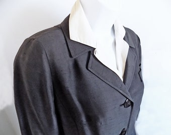 May include: A dark gray blazer with a white collar and a double breasted closure. The blazer has a classic tailored fit.