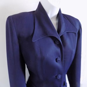 以下が含まれることがあります： 幅広の襟と3つのボタンが付いたネイビーブルーのブレザー。ブレザーは体にフィットしたシルエットで、長袖です。