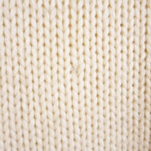 May include: Close-up of a white knitted fabric with a textured surface.