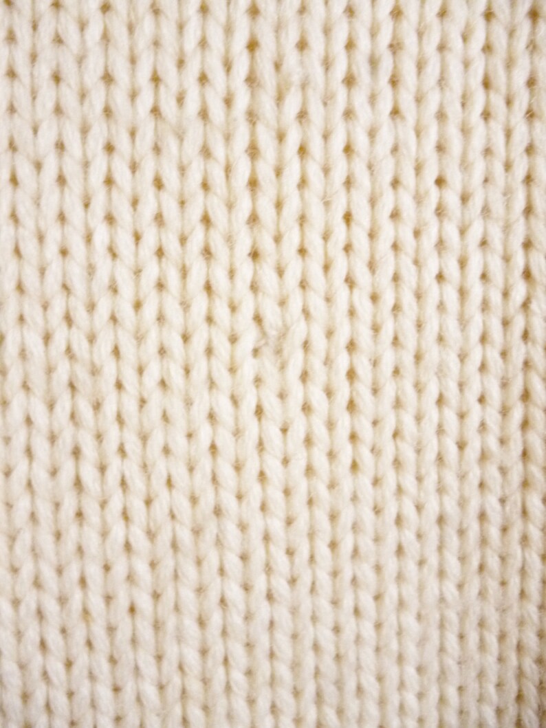 May include: Close-up of a white knitted fabric with a textured surface.