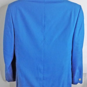 May include: A solid blue blazer with a single button closure. The blazer has a smooth, wrinkle-free finish.
