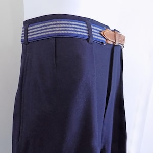 May include: Dark blue trousers with a blue and white striped belt and a brown leather buckle.