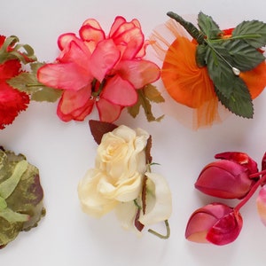 May include: Assortment of six artificial flower brooches in various colors and styles, including red, pink, orange, yellow, and green.