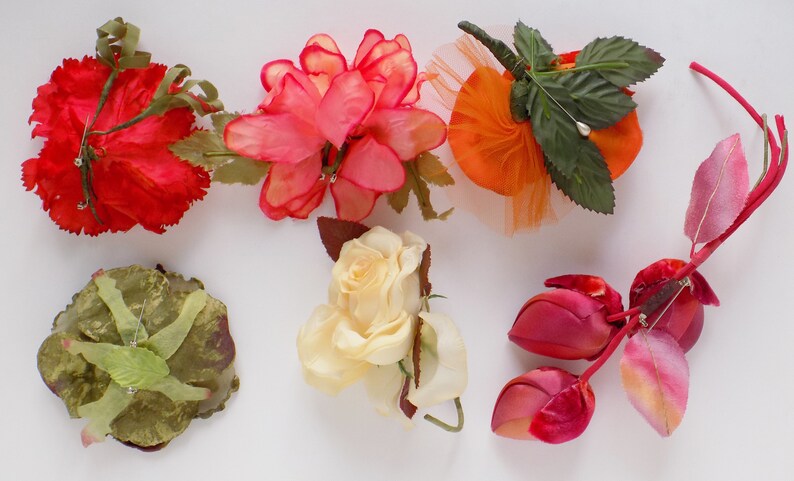 May include: Assortment of six artificial flower brooches in various colors and styles, including red, pink, orange, yellow, and green.
