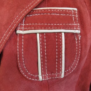 Puede incluir: Una chaqueta de gamuza roja con un bolsillo cosido blanco.