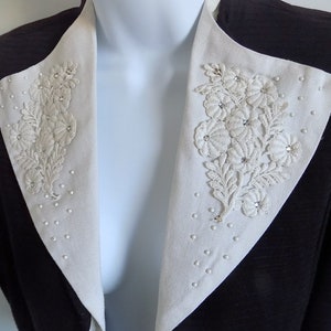 May include: A brown blazer with a white collar featuring a floral design with rhinestones.