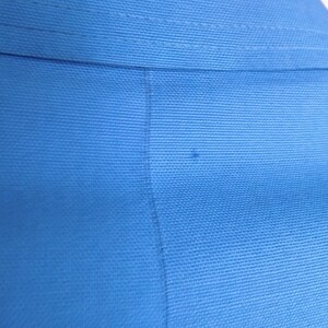 May include: Close-up of a blue fabric with a subtle texture. The fabric is smooth and appears to be woven.
