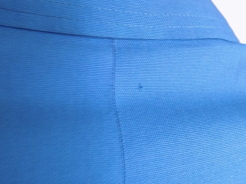 May include: Close-up of a blue fabric with a subtle texture. The fabric is smooth and appears to be woven.