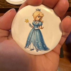 May include: A white ceramic mug with a black handle and the text "But First, Coffee" in a handwritten style. The mug is on a white surface. The mug is approximately 4 inches tall.