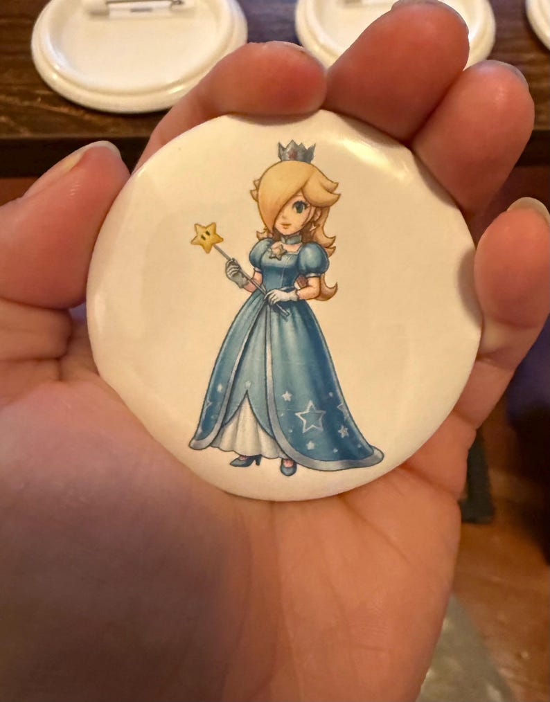 May include: A white ceramic mug with a black handle and the text "But First, Coffee" in a handwritten style. The mug is on a white surface. The mug is approximately 4 inches tall.