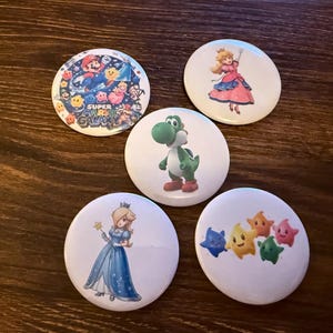 May include: A white ceramic mug with a black handle and the text "But First, Coffee" in a black, bold font. The mug is sitting on a white surface. The mug is approximately 4 inches tall.