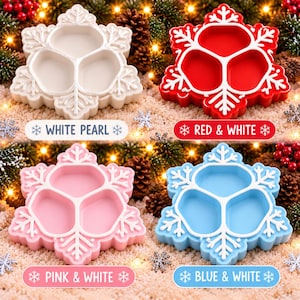 May include: Four snowflake-shaped serving trays with three internal compartments. The trays come in white pearl, red with white accents, pink with white accents, and blue with white accents. Each tray features a raised white snowflake pattern.