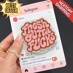 May include: A clear acrylic phone grip with the phrase "fresh outta fucks" in brown and pink, set against a pink Instagram-themed background. The image includes a "Best Offer" sticker and a "Next Day Shipping" banner.
