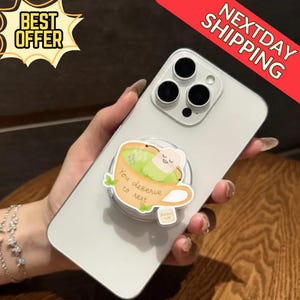 May include: A white smartphone with a pop socket featuring a cartoon teacup design. The pop socket has the text "You deserve to rest". The phone has a triple-lens camera. A "Best Offer" sticker is in the top left corner.