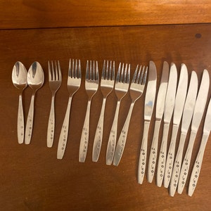 May include: A set of silverware with a floral design. The set includes forks, spoons, and knives.