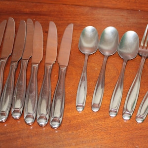 May include: A set of silverware, including knives, spoons, and forks, all made of polished stainless steel.