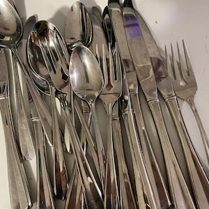 May include: A pile of silverware, including forks, spoons, and knives, all made of shiny stainless steel.