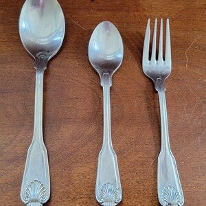 May include: A set of three silver-plated utensils, including a fork and two spoons, with a shell design on the handles.