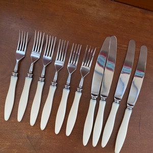 May include: Set of eight silver forks and three silver butter knives with white plastic handles.