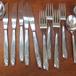 May include: A set of silverware with a floral design on the handles. The set includes spoons, forks, and knives.