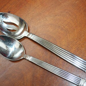 May include: Two silver spoons with ribbed handles. One spoon has a slotted bowl.