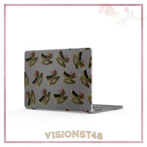 May include: A laptop computer with a gray case featuring a repeating pattern of gold and black abstract shapes with red accents. The laptop is open, displaying the keyboard and screen.