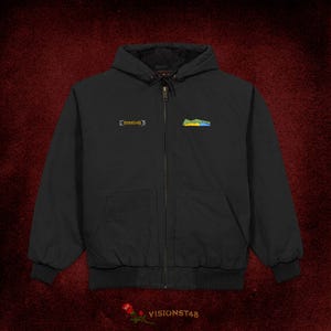 May include: Black hooded jacket with a zip fastening, embroidered text, and a colourful mountain graphic on the chest. The jacket has a ribbed hem and cuffs. The text "VISIONST48" is at the bottom of the image.