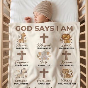 May include: A cream-colored baby blanket with the text "GOD SAYS I AM" and various inspirational words and Bible verses. The blanket features illustrations of animals like a giraffe, lion, and elephant. The name "Julian Hayes" and baptism date are also printed on the blanket.