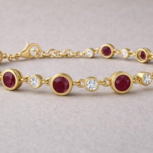 Può includere: Un bracciale in oro con alternanza di rubini rotondi e diamanti incastonati. Il bracciale ha una catena delicata e una chiusura sicura. I rubini sono di un rosso intenso e i diamanti brillano. Un gioiello raffinato.