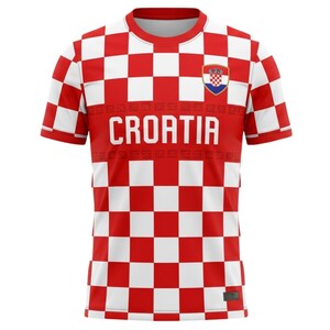 May include: Red and white checkered Croatia soccer jersey. The jersey features the word "CROATIA" in large white letters across the chest, with the Croatian coat of arms on the upper right chest. The sleeves and lower portion of the jersey have a checkered pattern.