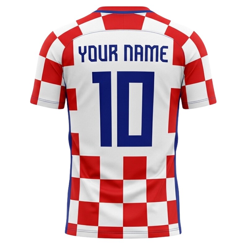 May include: A white, red, and blue soccer jersey with the text "YOUR NAME" above the number "10" in blue. The jersey has a checkered pattern on the sleeves and shoulders, with a solid white back panel.